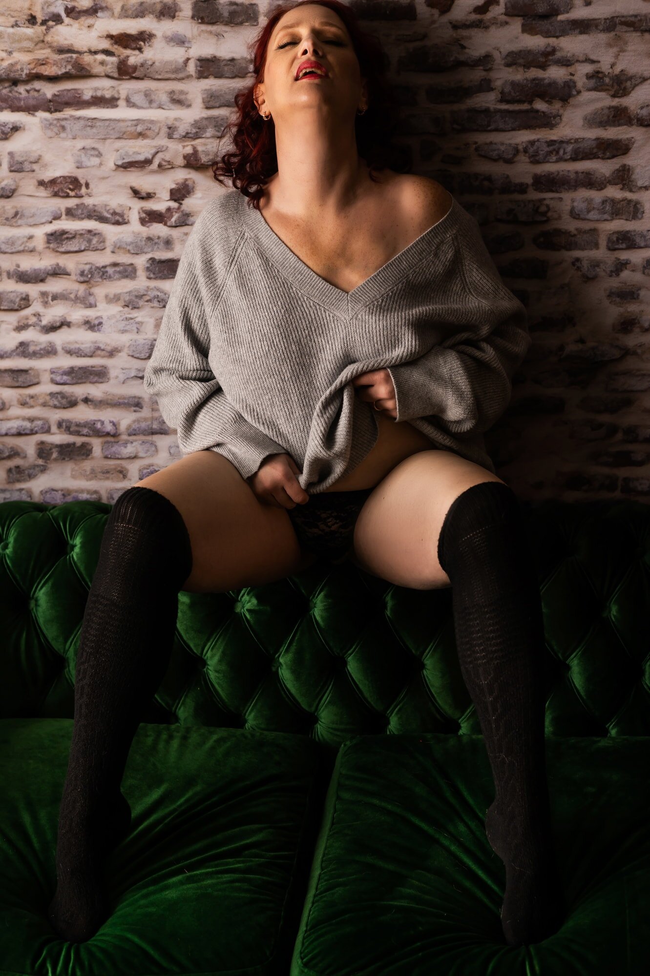 A woman poses in knee high socks and a sweater at a boudoir studio in rochester new york.